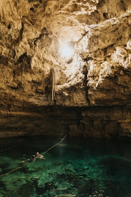 Visitors swimming joyfully in the refreshing turquoise waters of a hidden cenote.