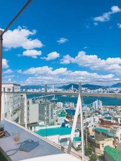 A vibrant cityscape background with a stylish tote bag resting on a café table, sunlight casting warm shadows.