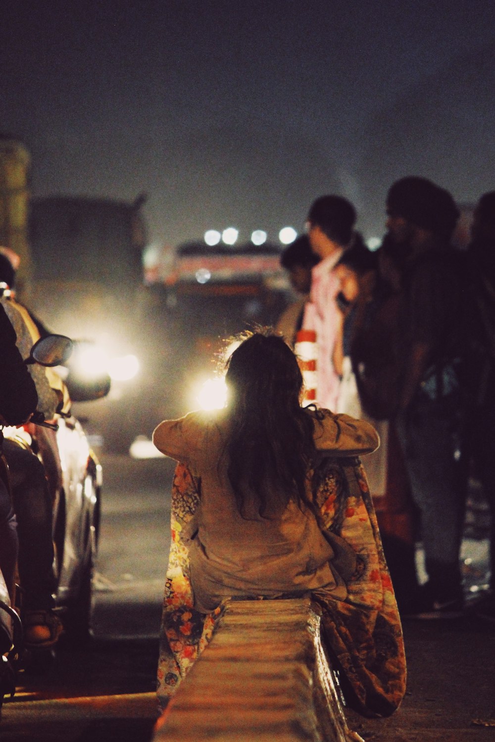 woman sitting on concrete barrier on street