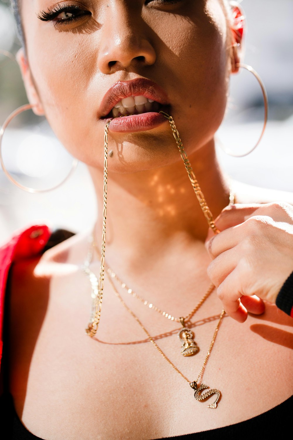woman biting gold-colored necklace