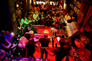 A candid shot of an intimate audience smiling and swaying to the music in a cozy venue.