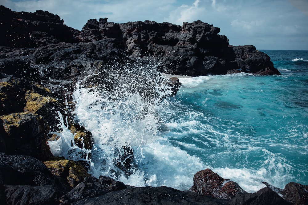 Le onde del mare spruzzano sulla formazione rocciosa durante il giorno