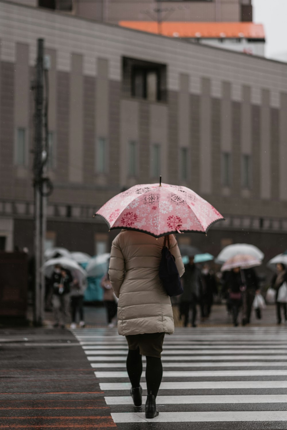 donna che cammina sul pedone mentre tiene l'ombrello