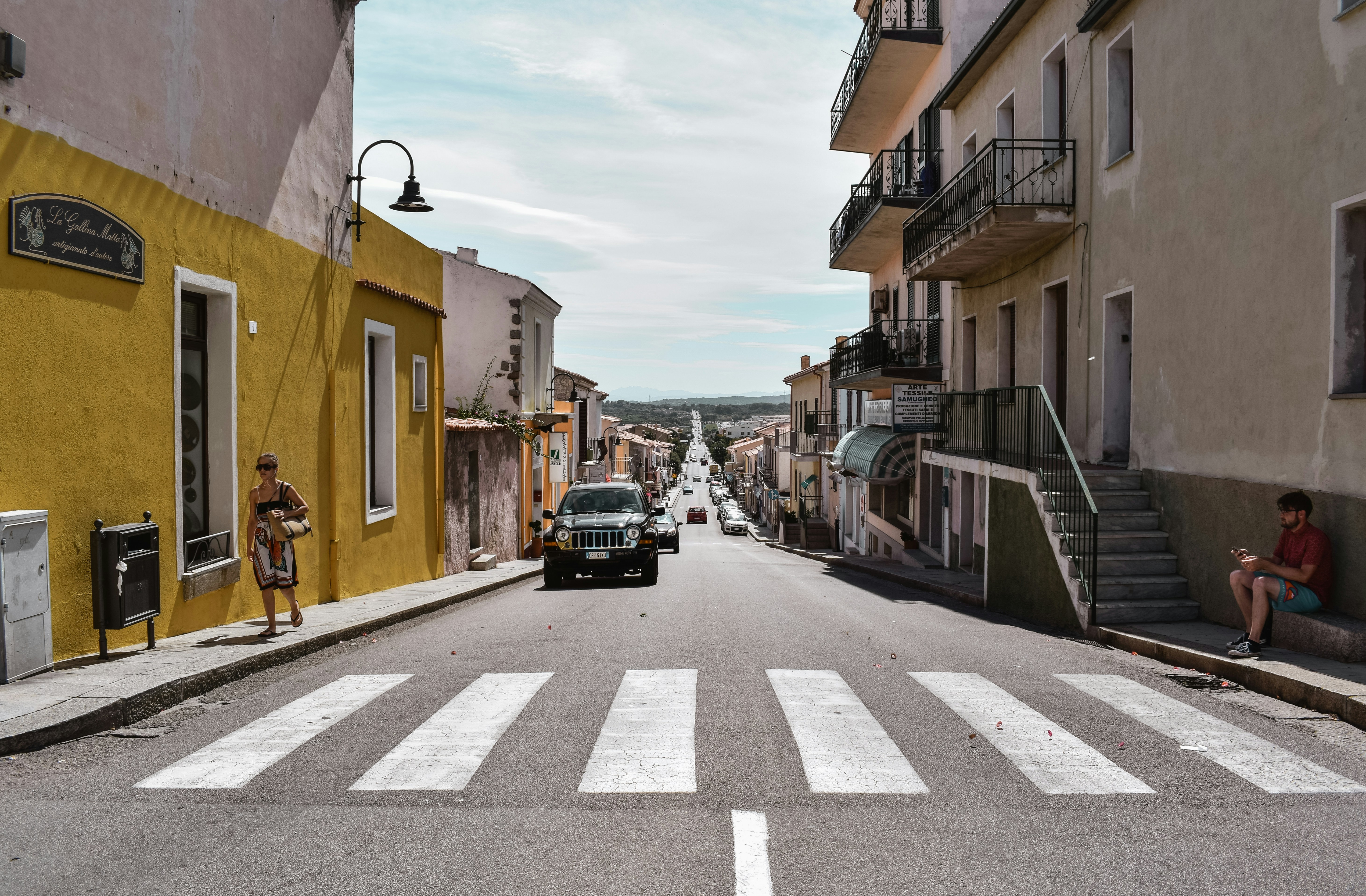 woman walking on sidewalk near pedestrian lane at daytime