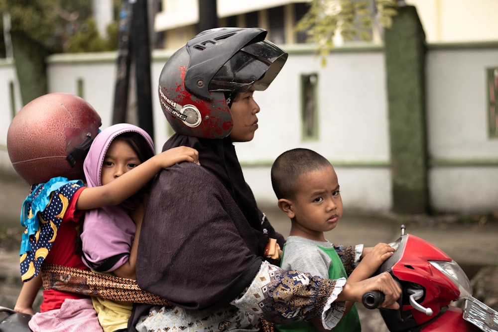 man riding motorcycle with 3 kids at daytime