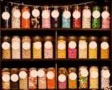 Stacks of sugar confectionery jars with vibrant labels on a store shelf.