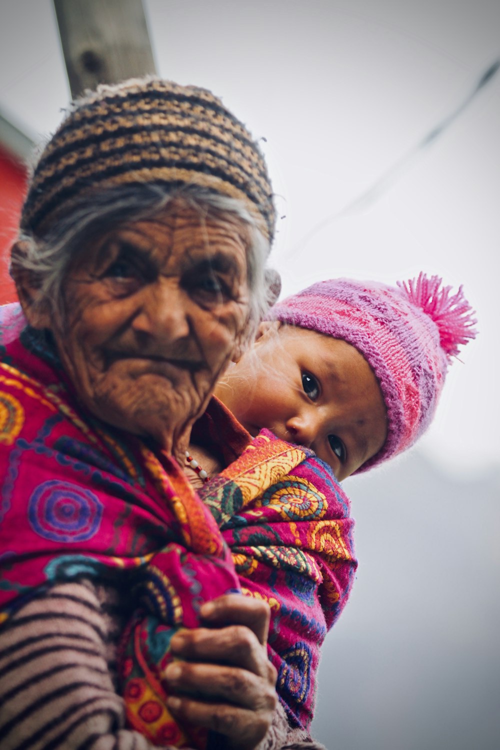 woman wearing multicolored blanket hugging the baby