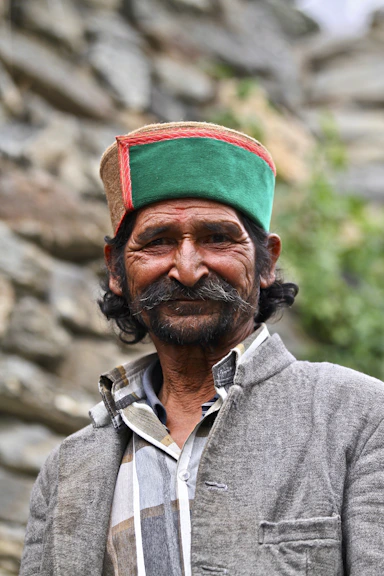 A man with a mustache wearing a traditional green and red cap