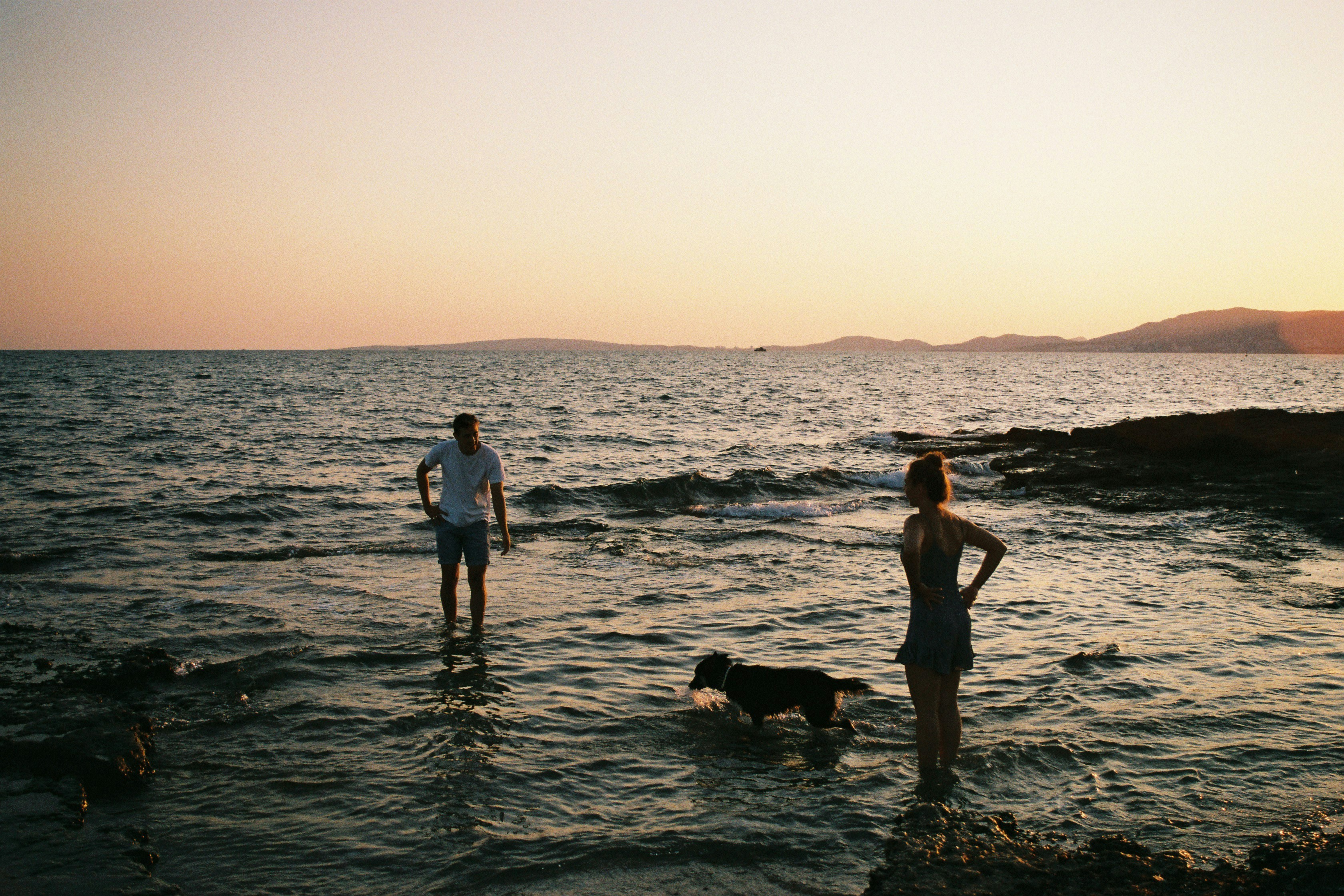uomo e donna in piedi sul mare durante l'ora d'oro