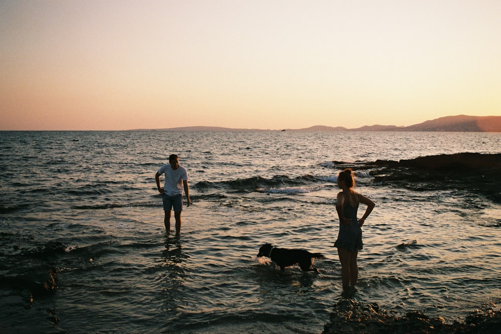 man and woman standing on sea during golden hour