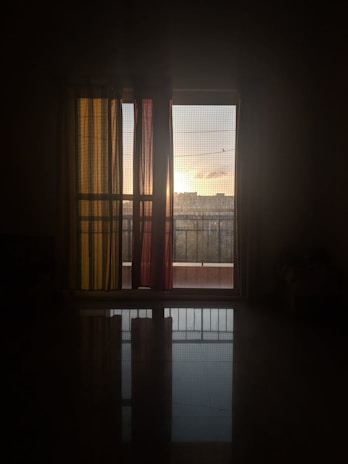 A modern living room with large windows fitted with pleated mosquito nets, softly filtering the sunlight.