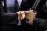A close-up of hands holding tickets and wearing wristbands from various sporting events across America.