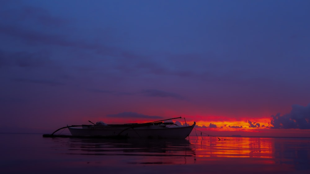 white boat under cloudy sky during sunset