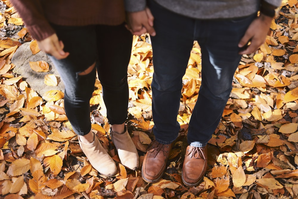two person standing on dried leaves at daytime