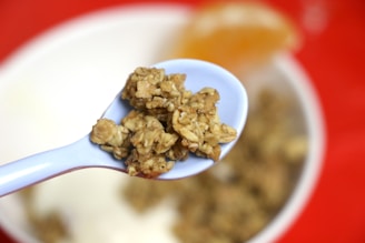 Close-up of a wooden spoon scooping bran flakes from a rustic bowl against a dark orange background.