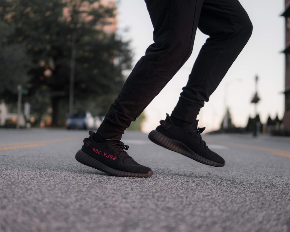 黒と赤の adidas Yeezy Boost 350 v2 スニーカーを履いている人の写真 – Unsplashの無料フィート写真