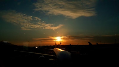 Sunset over the plots with the silhouette of Jewar Airport in the distance.