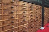 A wooden cabinet with multiple small drawers featuring labels with black text, possibly in a traditional Asian script. Each drawer has a small round handle. The wood appears aged, contributing to a rustic and antique aesthetic.