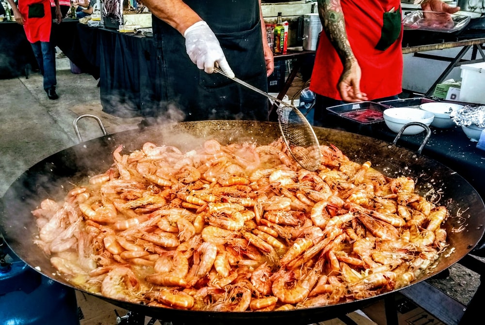 person cooking fried shrimps