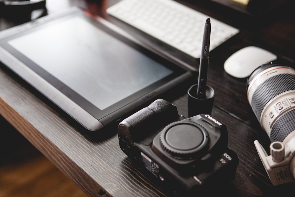 Canon camera body beside black tablet computer