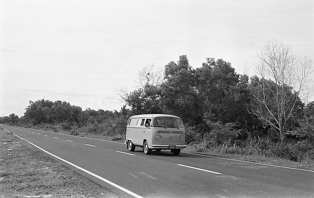 grayscale photography of Volkswagen T2 on the road near trees
