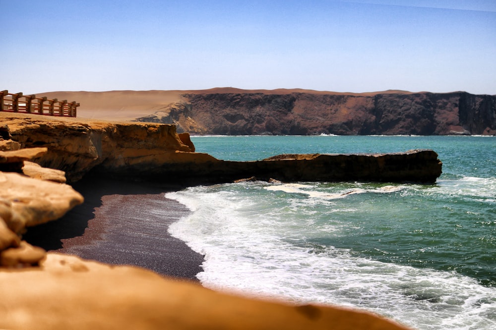 wide angle photography of brown cliff near body of water