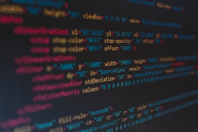 A close-up view of colorful HTML and CSS code displayed on a computer screen. The lines of code are predominantly highlighted in shades of blue, red, orange, and yellow on a dark background, indicating syntax highlighting for readability.