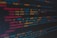 A close-up view of colorful HTML and CSS code displayed on a computer screen. The lines of code are predominantly highlighted in shades of blue, red, orange, and yellow on a dark background, indicating syntax highlighting for readability.