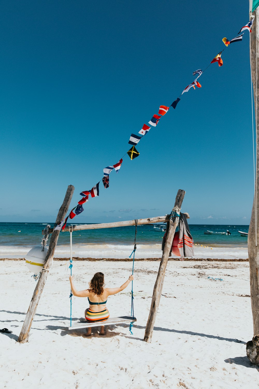 woman sitting on swing near sea shore