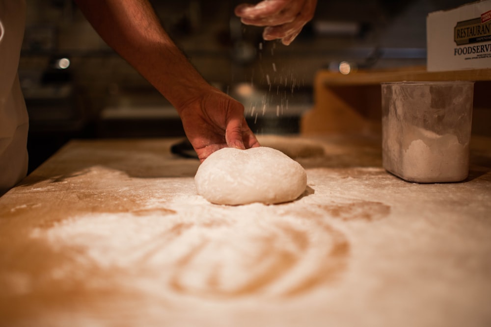 person holding bread dough on table