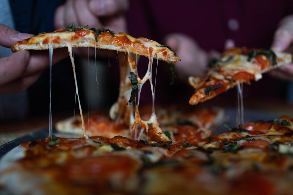 Person, die geschnittene Pizza pflückt