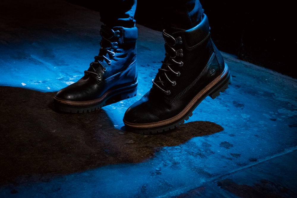 Persona con botas de trabajo negras de pie sobre una superficie de hormigón