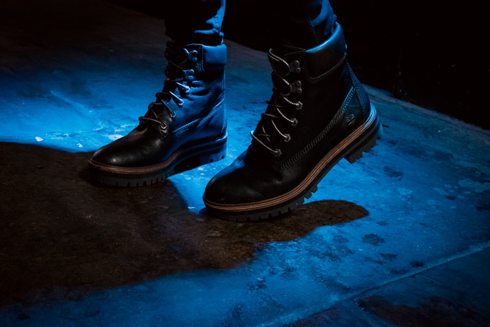 person wearing black work boots standing on concrete surface