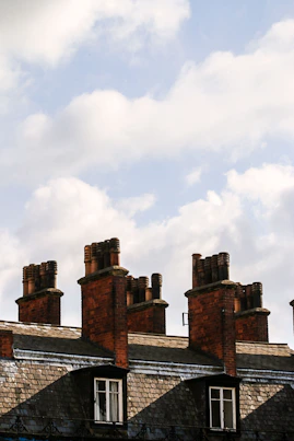 A chimney sweep carefully cleaning a traditional brick chimney on a cozy home in Torrington.