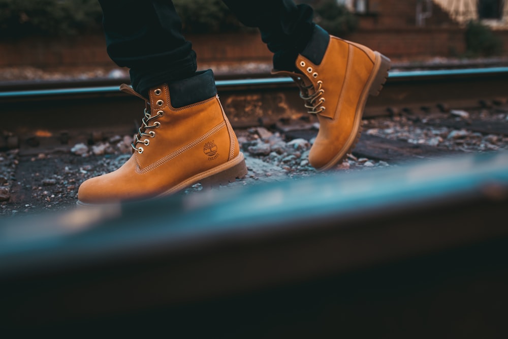 Une personne marche sur une voie ferrée portant une paire de bottes Timberland jaunes