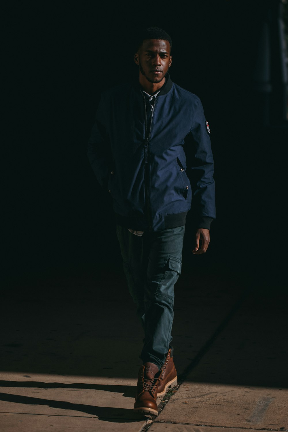 man wearing blue jacket and brown leather boots