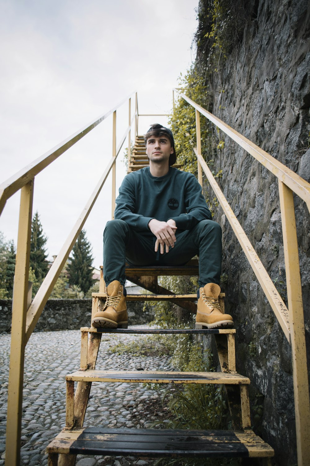 Mann sitzt auf Metalltreppe