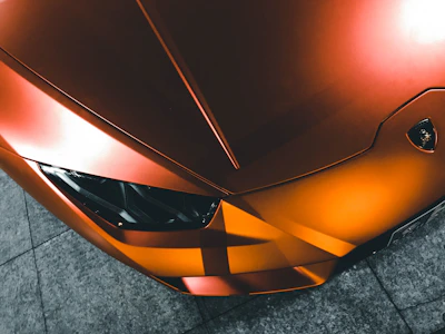A magnifying glass focusing on a sleek car silhouette with an orange target symbol in the background.