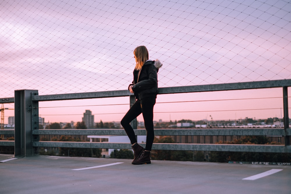 A woman poses wearing a Timberland jacket and boots in front of a purple sky