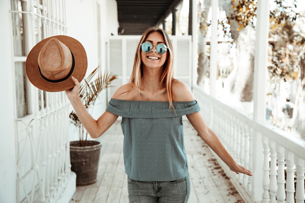 Mujer con blusa gris con hombros descubiertos sosteniendo su gorra