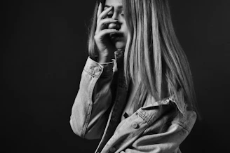 woman in denim jacket covering her face with her palm