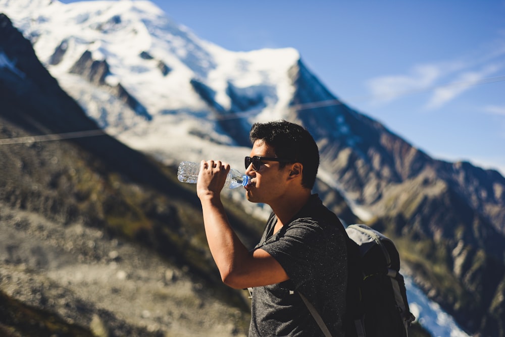 man drinking water at top of mountain