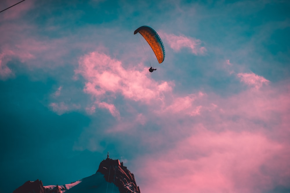 person with parachute by mountain