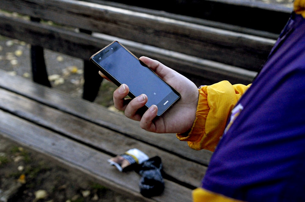 person standing and holding black smartphone