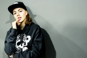 Close-up image of a male model wearing a minimalist black hoodie with a confident urban pose.