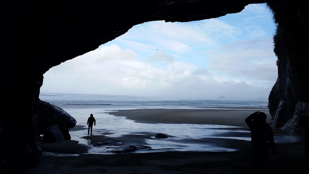 man by cave and shore
