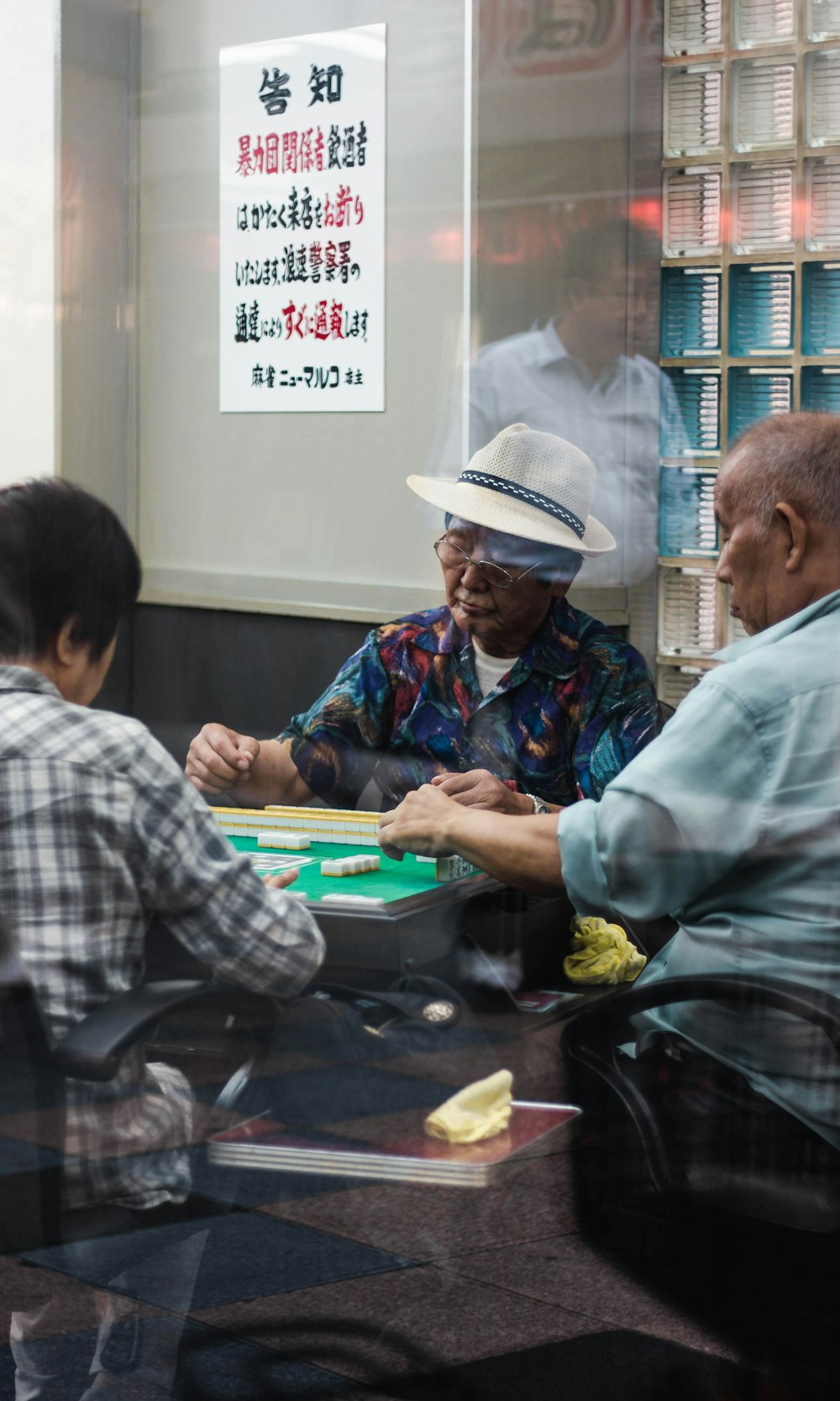 three man sitting playing mahjong inside room