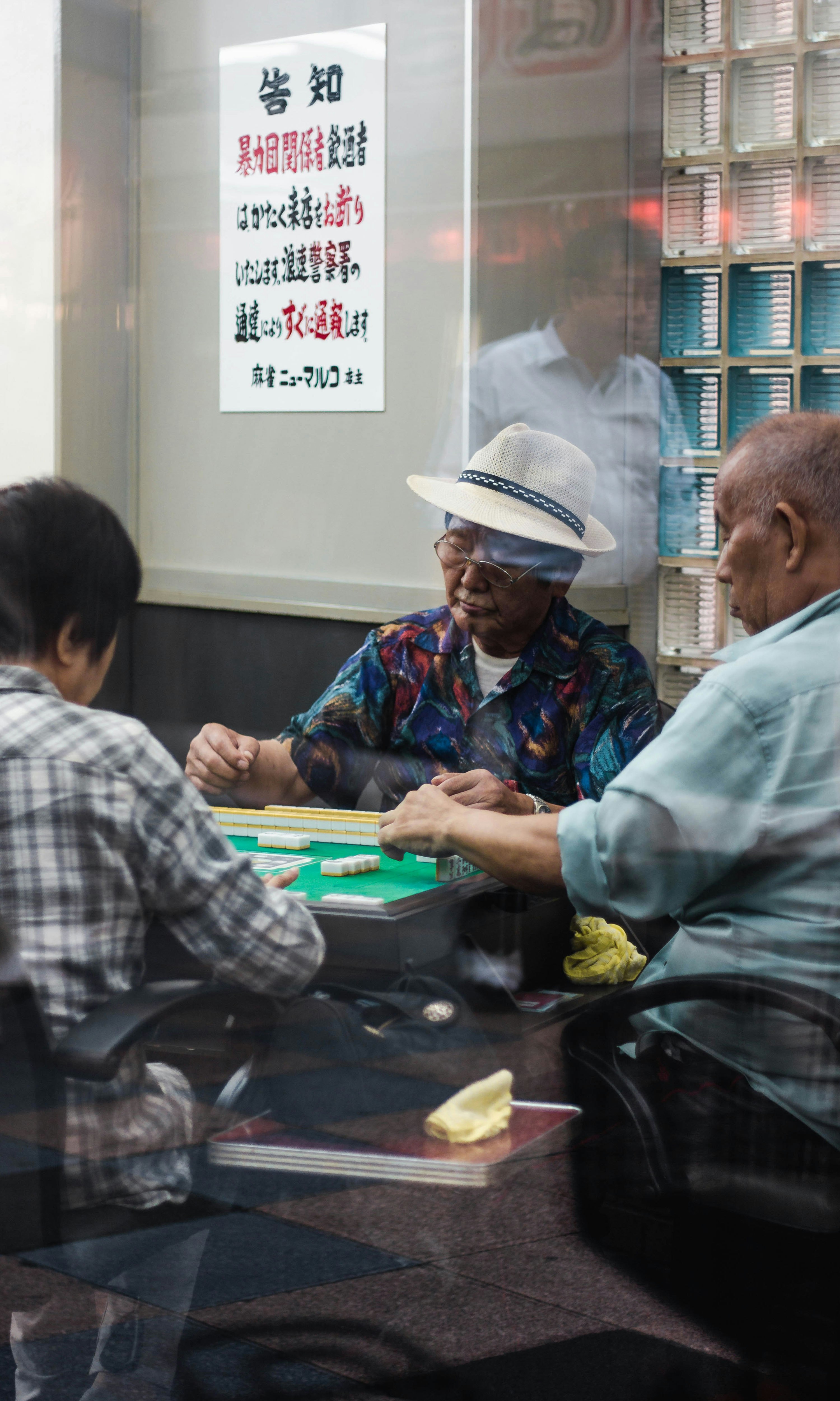 three man sitting playing mahjong inside room