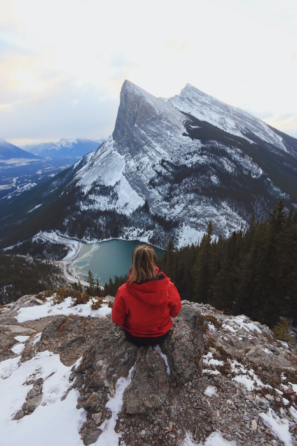 person sitting on rocky hill viewing mountain