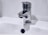 A chrome faucet is mounted on a white sink. A small stream of water is dripping from the tap's spout into the basin below. The background is a plain light color, enhancing the metallic shine of the faucet.